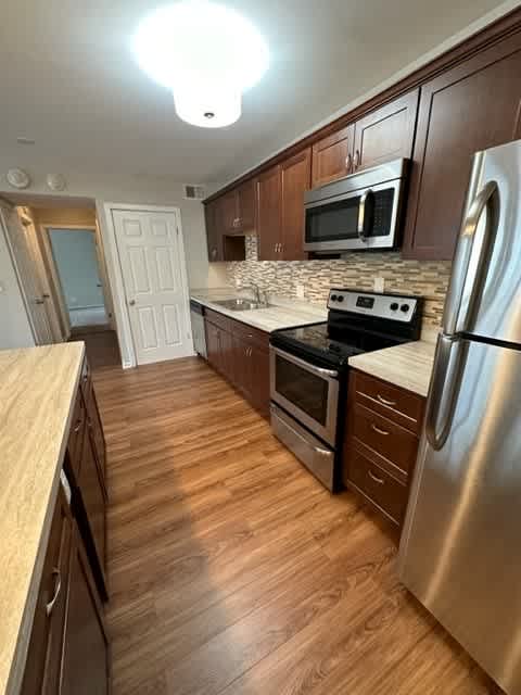 a kitchen with wood floors and stainless steel appliances