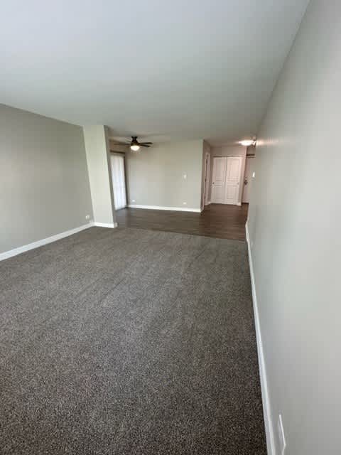 an empty living room with a ceiling fan