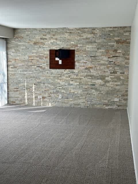 an empty room with a brick wall and a television