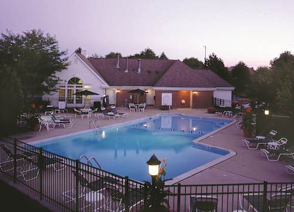 A pool and patio area of a house with a lamp post in the foreground.