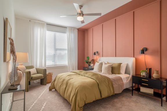 a bedroom with a pink accent wall and a bed with a white headboard