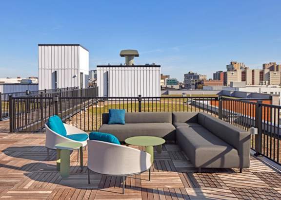 A patio with a white couch, green cushions, and a table with a green top.
