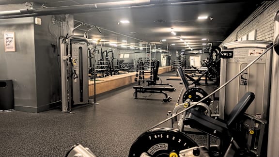 A gym with a variety of equipment including a squat rack, a leg press machine, and a bench press.