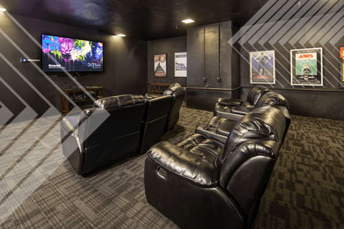 A black leather couch in a room with a TV screen showing a colorful image.