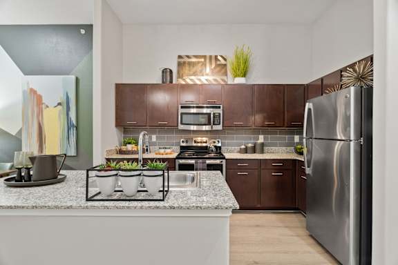 A modern kitchen with a white countertop and stainless steel appliances.