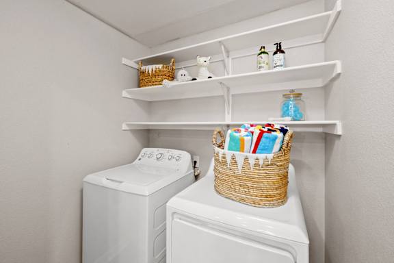 the laundry room has a large washer and dryer and a basket with towels