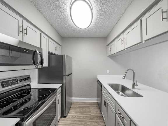 A kitchen with a stove, refrigerator, and sink.