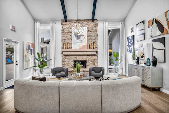 A living room with a stone fireplace and a grey sofa.