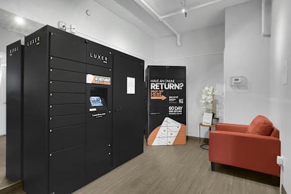 A black locker with the word LUXER on it is next to a sign that says "Have an ounce? Return here."