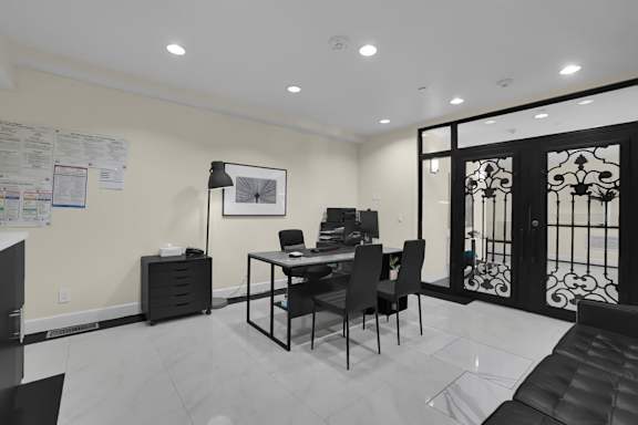 A black and white photo of a room with a desk and chairs.