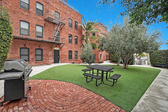 A brick building with a fire escape and a picnic table in front.