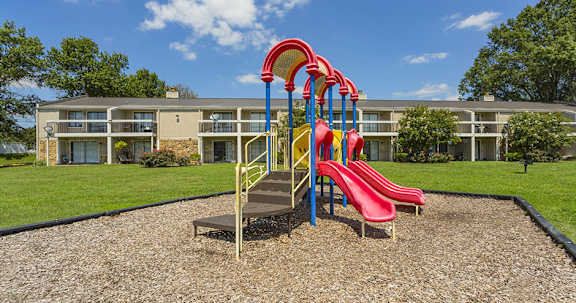 A playground with a red slide and a yellow slide.