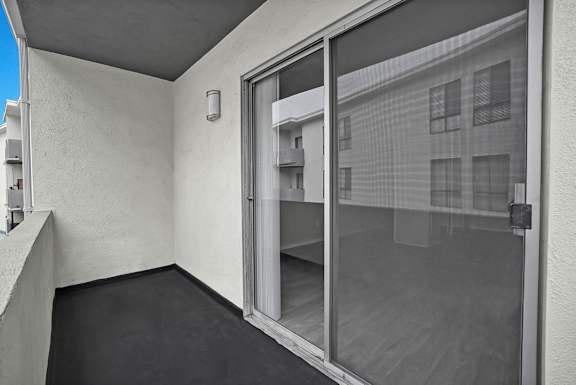 A balcony with a glass door leading to a building.