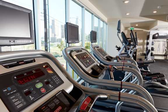 A row of treadmills in a gym with a digital display showing the time.