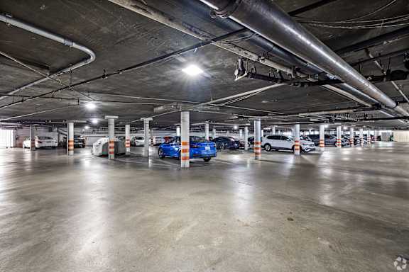 A parking garage with a blue car in the foreground.