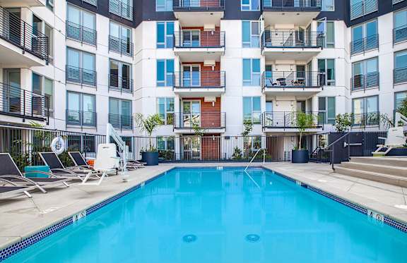 A large swimming pool in front of a multi-story apartment building.