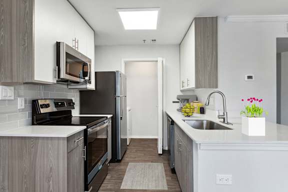 A modern kitchen with a refrigerator, microwave, oven, and sink.