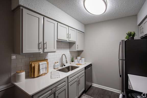 A kitchen with a black refrigerator and white cabinets.