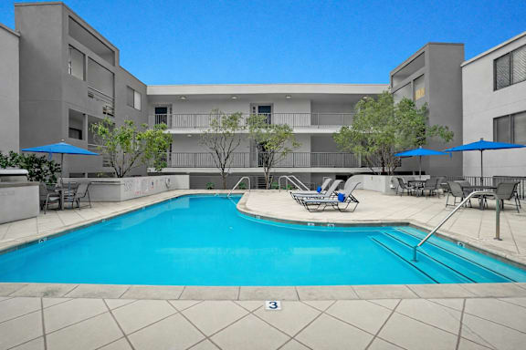 A swimming pool in front of a building with a clear blue sky.