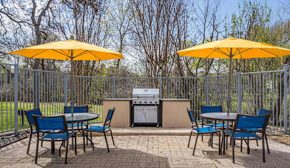 A patio with a table, chairs and umbrellas.