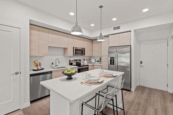 A modern kitchen with a white island and stainless steel appliances.