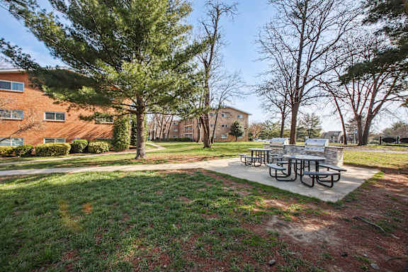 A park with a picnic table surrounded by trees and apartment buildings.
