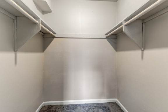 A white wall with a grey carpet and a white ceiling with a vent.