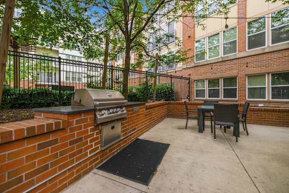 A patio with a grill and chairs.