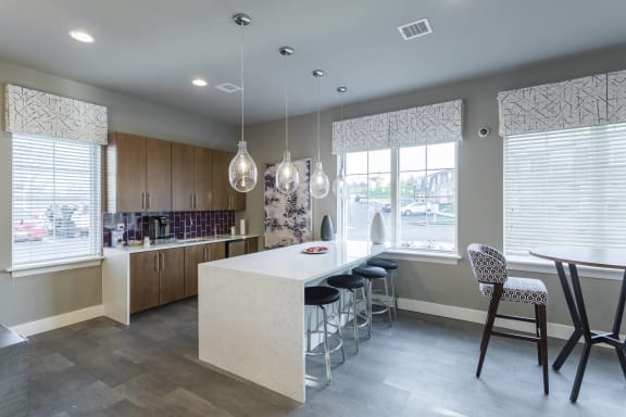 a kitchen with a large island and stools in front of a table with chairs