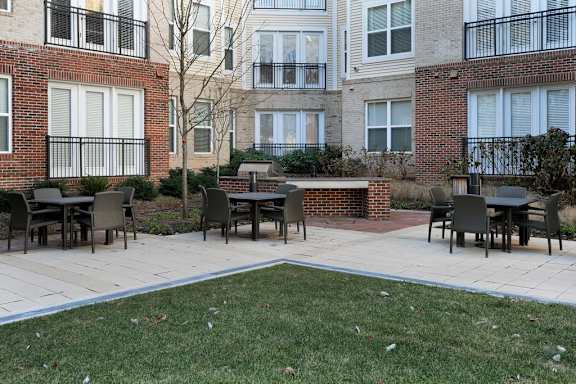 A patio with chairs and a table in front of a brick building.