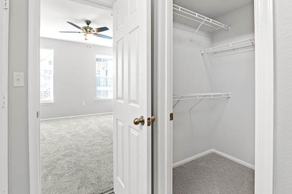 A white door is open to a room with a ceiling fan.