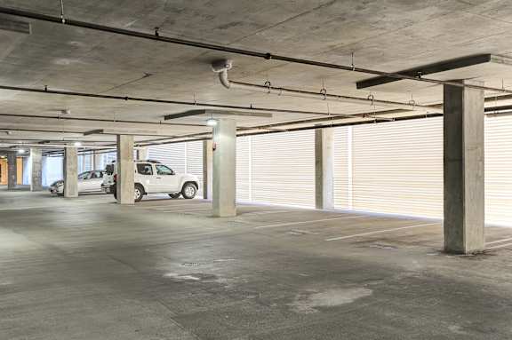 A parking garage with two cars parked in it.