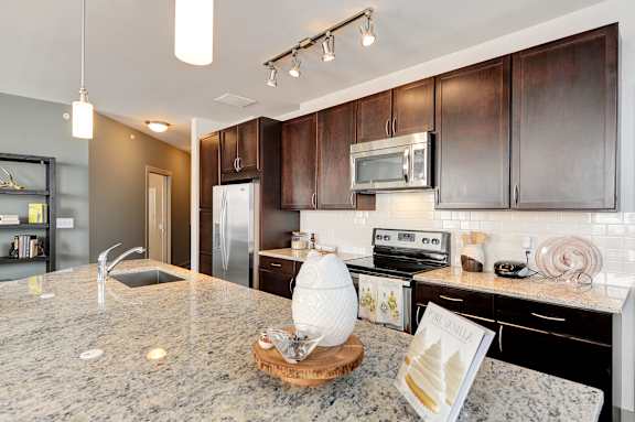 A kitchen with dark brown cabinets and granite countertops.