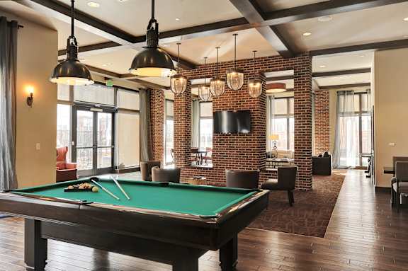 A pool table is in the middle of a room with a brick wall.