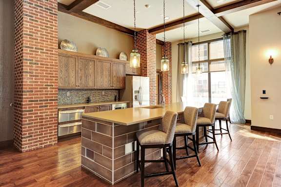A kitchen with a brick wall and wooden floors.