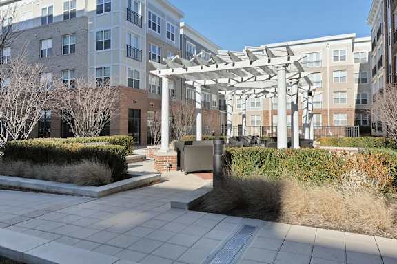 A modern building with a white pergola and a brick pillar.