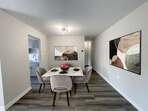 A dining room with a table set for two and a painting on the wall.