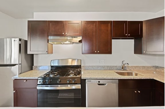 A kitchen with a stove, sink, and refrigerator.