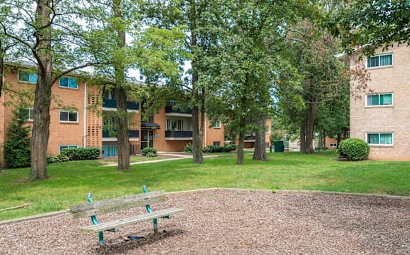 A park area with a bench and a building in the background.