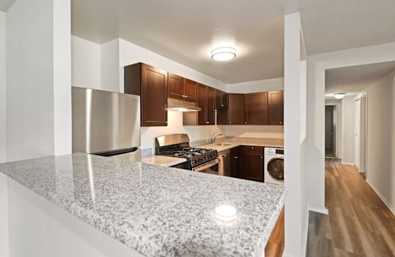 A kitchen with a granite countertop and wooden cabinets.