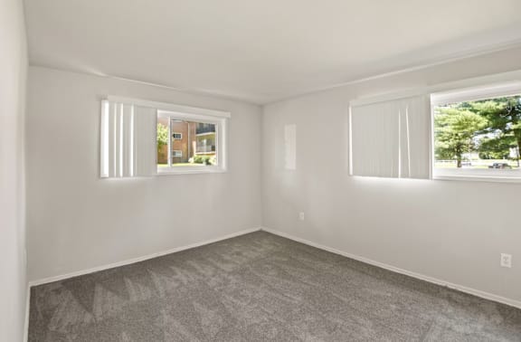 A room with two windows and a carpeted floor.