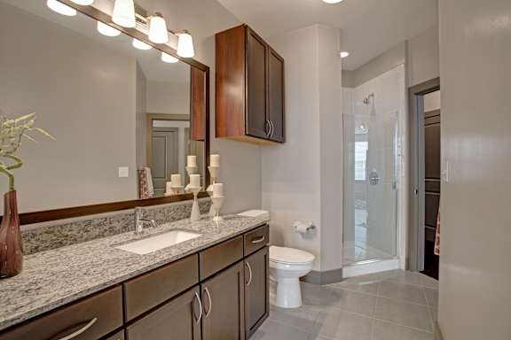 A bathroom with a sink, toilet, and mirror.
