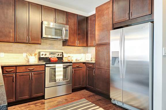A kitchen with wooden cabinets and a stainless steel refrigerator.