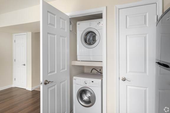 A white door is open to reveal a washing machine and dryer in a laundry room.