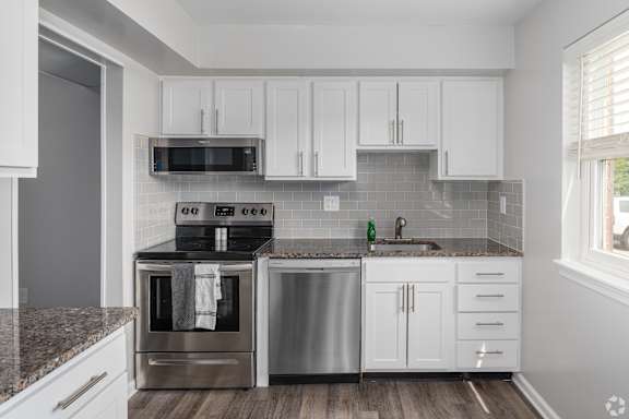 A kitchen with white cabinets and a stainless steel oven and sink.