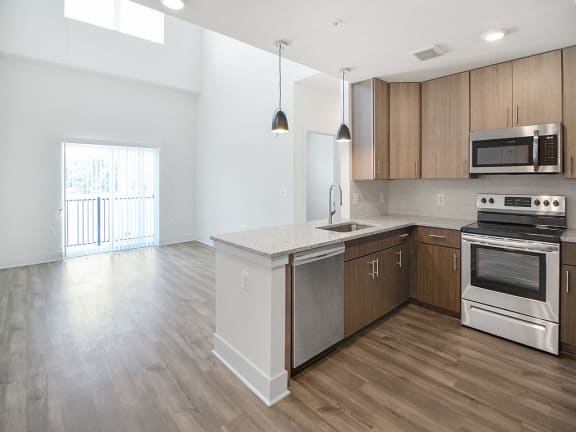 an empty kitchen with stainless steel appliances and wooden cabinets
