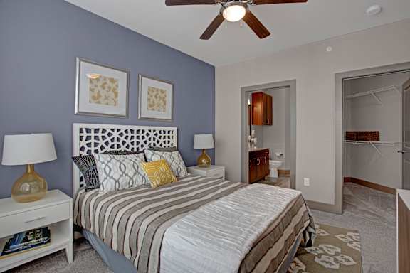 A bedroom with a bed, two lamps, and a ceiling fan.