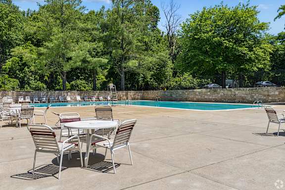 A table and chairs are set up on a patio next to a pool.