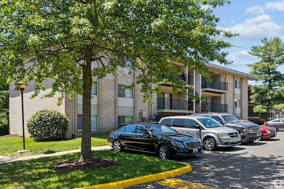 A black car is parked in a parking lot in front of a building.