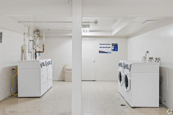 A laundry room with washing machines and dryers.